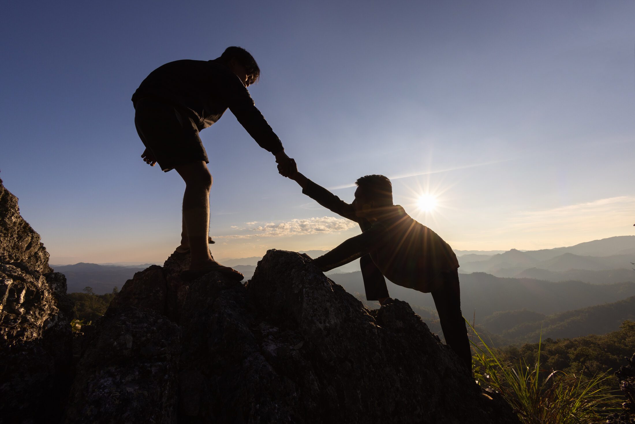 Silhouette Of Helping Hand Between Two Climber. Couple Hiking H